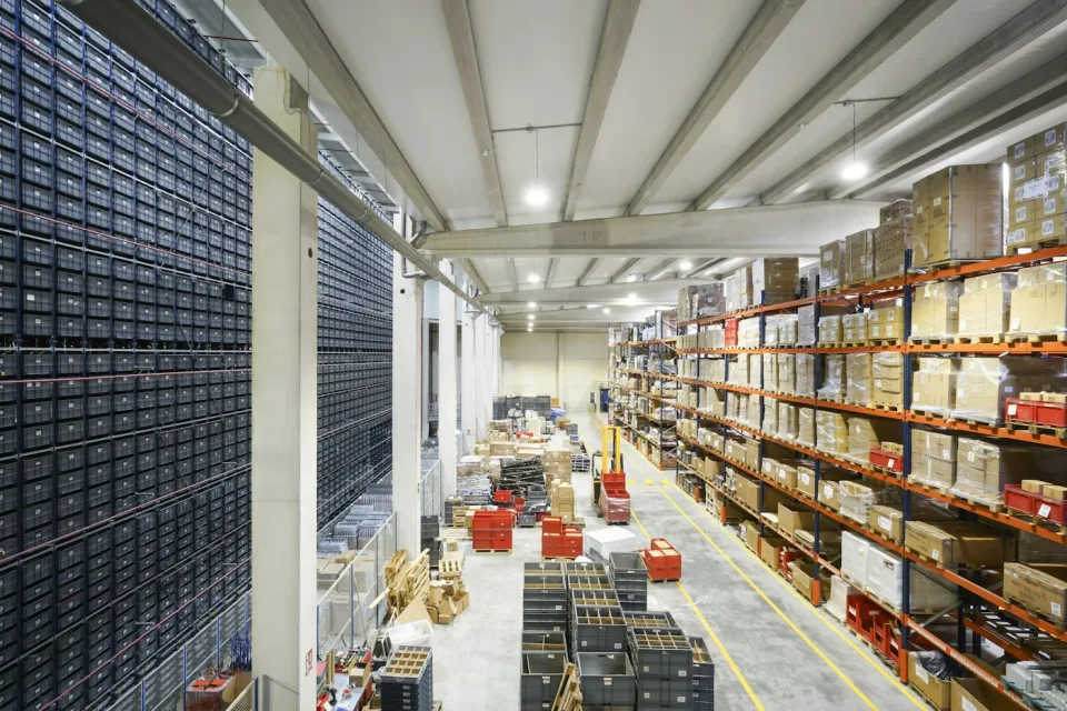 Düzenli raflarda paketlenmiş ürünlerin bulunduğu bir depo; temsili fotoğraf
